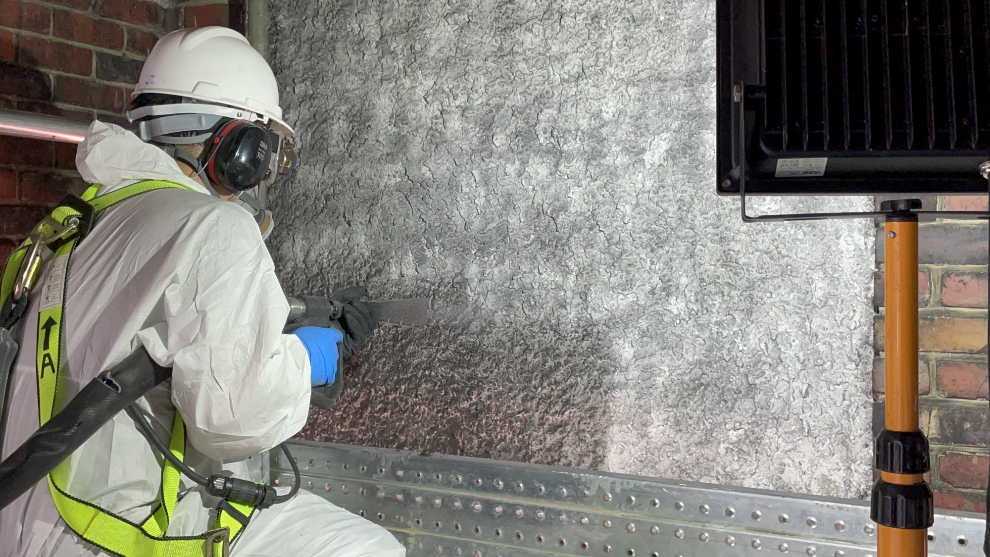 Technician applying surface treatment to a cleaned wall in a commercial building interior